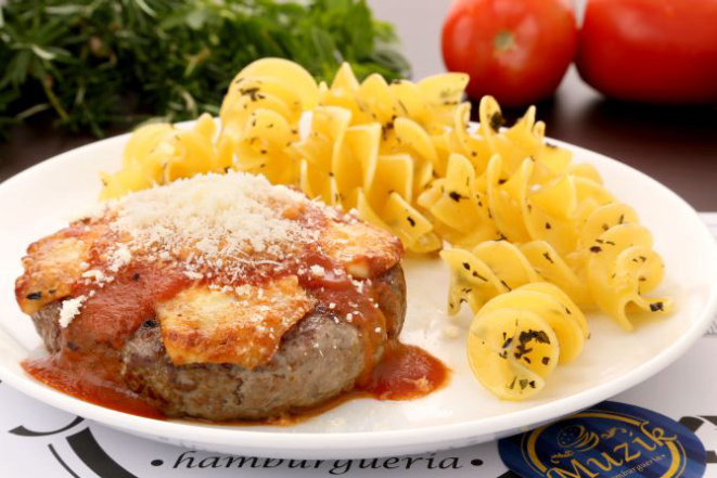 Hambúrguer aberto à parmigiana vem com granfusilli na manteiga de ervas e broto de feijão com legumes e cogumelos Paris (R$ 24,90). Foto: Jorge Mariano/Divulgação.