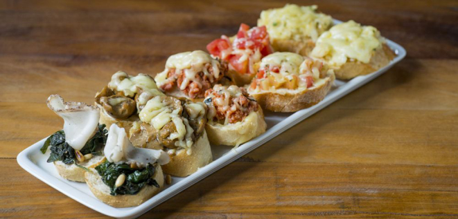 A sequência de mini bruschettas (R$ 35) é um dos novos pratos. Vem com duas de cada sabor: bacalhau, cogumelo, linguiça toscana, tomate e espinafre com lardo (um bacon nobre que o chef serve em outros pratos do restaurante). Foto: Nilo Biazzetto Neto / Divulgação.