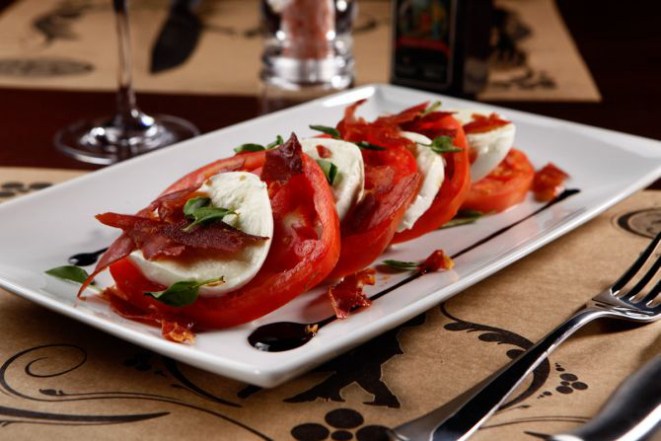 A salada Caprese leva tomates, presunto cru, muçarela de búfala, crema de aceto balsâmico e manjericão fresco (R$ 43). Foto: Divulgação.