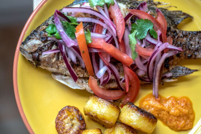 Whole tilapia with browned plantains, homemade hot sauce and a salad of onions, tomatoes and herbs in Sheffield, England, Dec. 19, 2016. ÒFlavour: Eat What You LoveÓ is the second cookbook written by Ruby Tandoh, who delights in preparing food without strictly adhering to rules. (Andrew Testa/The New York Times)