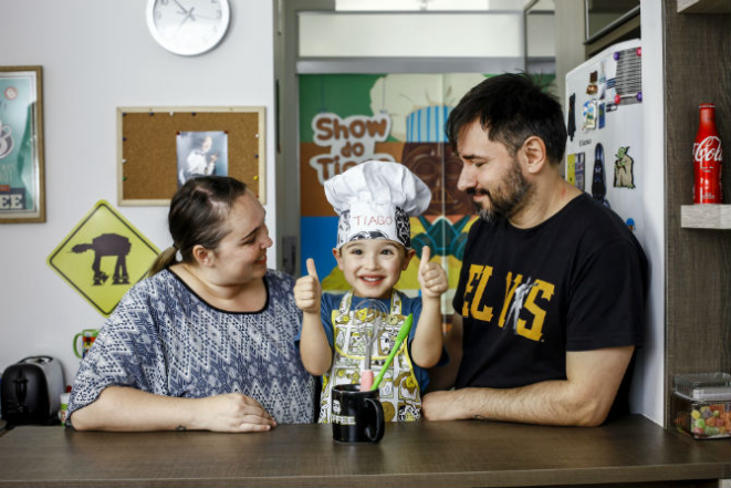 Tiago na cozinha de casa com os pais. Foto: André Rodrigues.