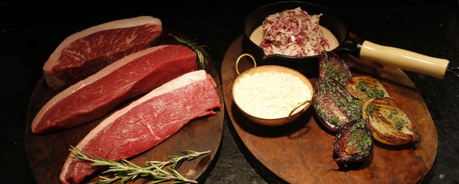 De cima para baixo: picanha de wagyu, picanha de nelore e picanha de angus. Ao lado, os acompanhamentos do prato: coleslaw (repolho cru com molho), banana frita, cebolas assadas e arroz branco. Foto: Grasilei Félix/Divulgação.