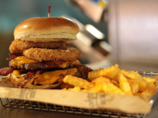 Um dos destaques do cardápio é o Smoke House (R$ 33,90 na versão simples / R$ 39,90 com dois hambúrgueres), que vem com bacon, onion rings, queijo cheddar e molho barbecue. (foto: divulgação)