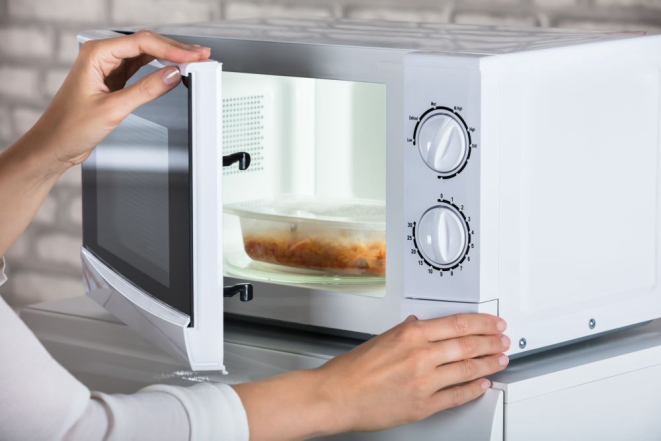 Woman's Hands Closing Microwave Oven Door And Preparing Food At Home