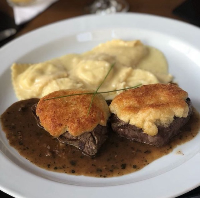 No La Palma, um dos pratos aclamados é o escalope de filé em crosta ao molho de ervas, acompanhado de ravioli da casa recheado de muçarela. Foto: Divulgação/Instagram<br>