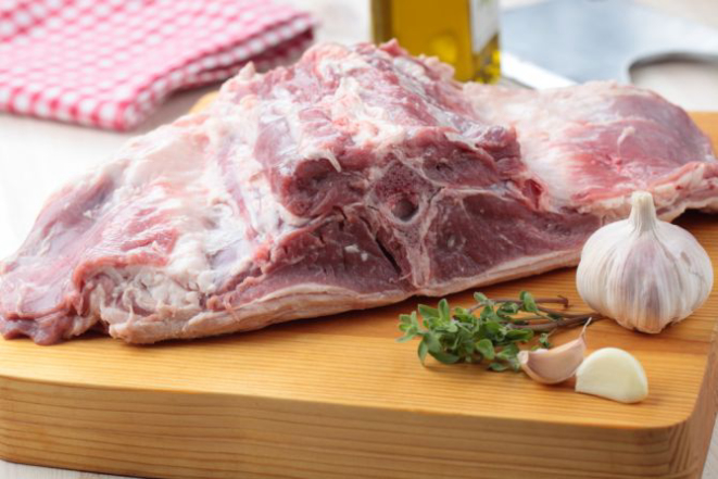 Raw saddle of lamb with garlic and thyme on a cutting board