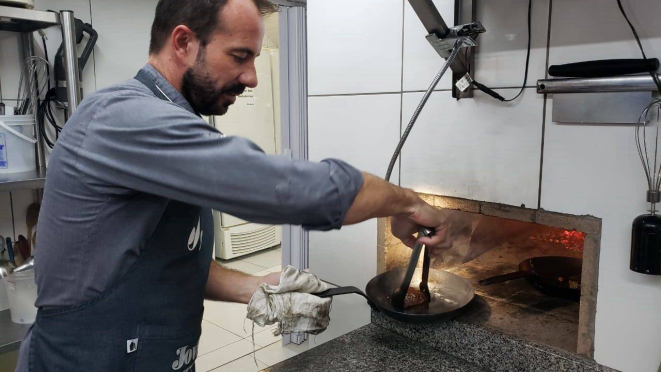 Chef Giuliano Hahn dando um trato no mignon que está sendo preparado no forno. 