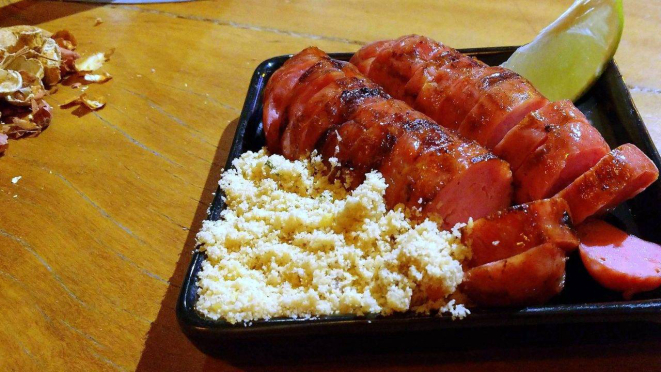 As cascas dos amendoins consumidos, para serem jogadas no chão, e a linguiça com farofa, de aperitivo.