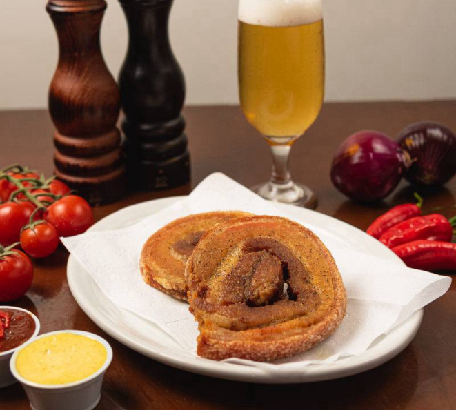 Torresmo de rolo, com 350g da barriga de porco crocante, servido acompanhado de fatias de limão e uma goiabada de pimenta feita ali mesmo.