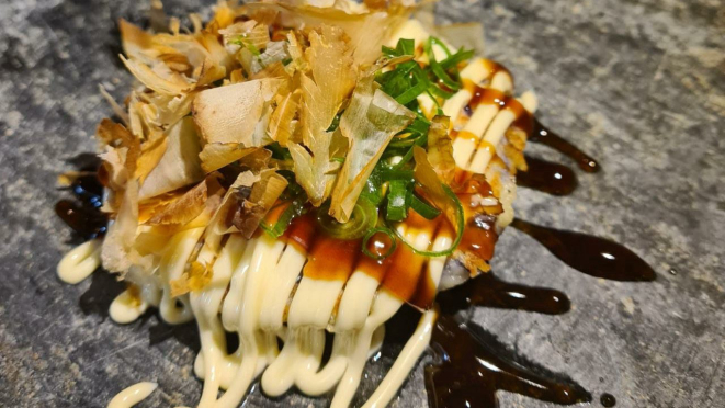 Okonomiyaki, uma espécie de panqueca japonesa, feita com cará, recheada com camarão rosa e finalizada com molho de ostra e Katsuobushi - um dos itens do Omakaze.