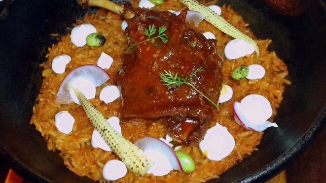 Pato Nikkei, um arroz salteado com temperos peruanos e aïoli, sobre o qual vem uma coxa de pato confitada ao molho hoisin.