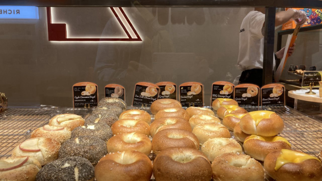 A Terra dos Bagels te convida a passear pela vitrine por um cardápio com 11 bagels com massas, recheios e coberturas que te fazem escolher com a ajuda do unidunitê. Alinhados cuidadosamente parecem desejar pular um a um no seu prato. 