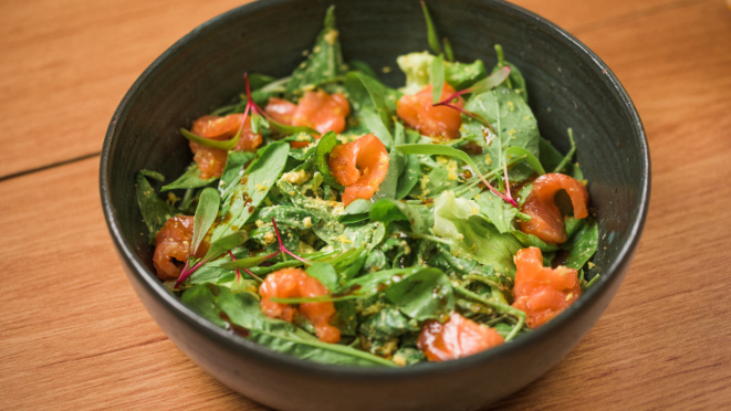 Salada de salmão - um mix de folhas, salmão curado, molho de limão e castanhas. É finalizada com tarê da casa e raspas de limão