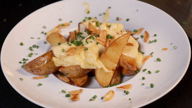 Raclette servida sobre bife de chorizo grelhado, alho confitado e batatas rústicas, do Valais Koffee Bar. 