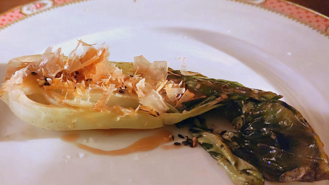 Bok choy grelhado na manteiga, servido com vinagrete de gergelim e katsuobushi.