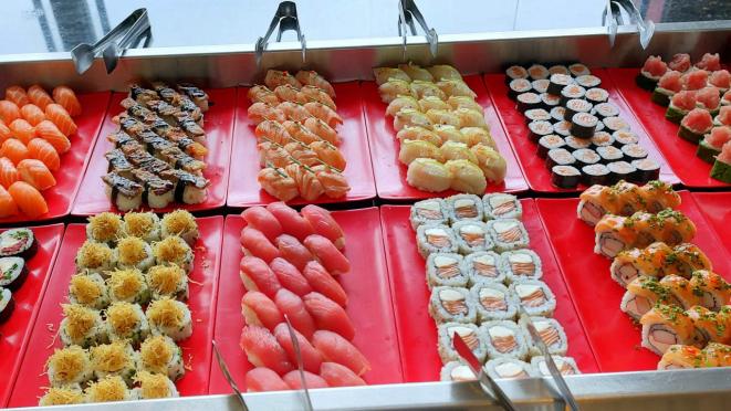 Sushis diversos disponíveis num balcão refrigerado. 