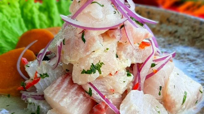 Ceviche clássico: cubos de tilápia fresca, temperados com limão, sal, coentro, pimenta dedo-de-moça e leche de tigre, complementados com cebola roxa, mini milhos, batata-doce glaceada e chips de aipim.