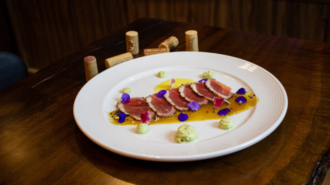 Carpaccio de magret de pato, com a técnica francesa e interferência do norte do Brasil: tucupi e jambu. 