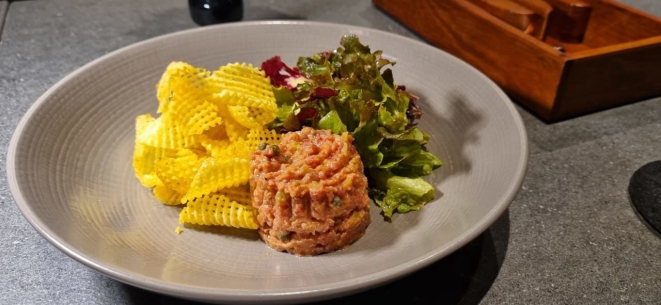 Steak tartare de mignon angus com chips de batatas e saladas de folhas ao vinagrete de mostarda dijon.