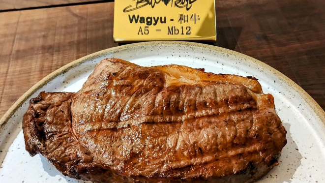 Carne de wagyu já grelhada, com a placa dourada a ser gravada com o nome do cliente, para registrar o momento. 