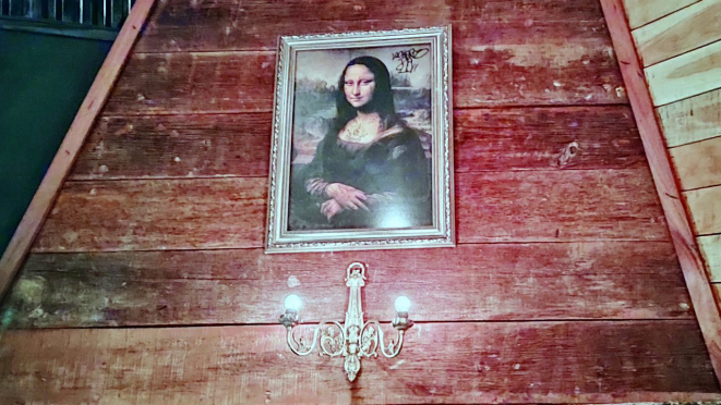 La do alto, na parede, a Mona Lisa tatuada acompanha todo o movimento da casa. 