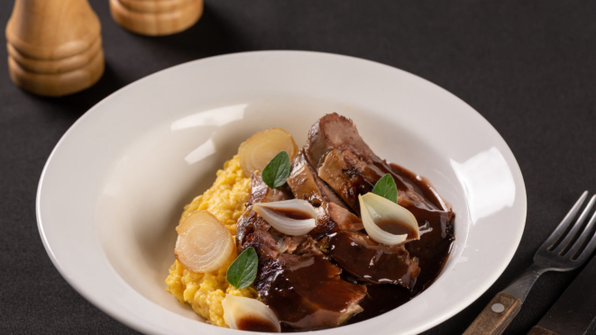 No Tierra Del Fuego, cordeiro assado na brasa com molho de vinho malbec, humita e cebola caramelizada. O restaurante também tem outras opções com carne no menu.