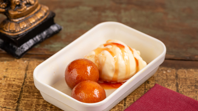 Gulab jamum que é uma bolinha feita com leite em pó, mergulhada em calda doce e sorvete de creme no Swadisht.