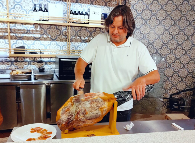 Chef Dudu Sperandio fatiando o jamón no balcão de seu novo empreendimento, Mercearia Avenida. | Foto: Anacreon de Téos