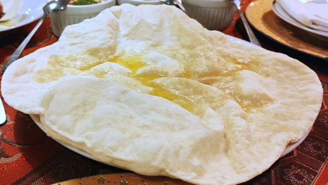 O pão árabe chega sempre quentinho e inflado à mesa, já para abrir o apetite dos comensais. | Foto: Anacreon de Téos