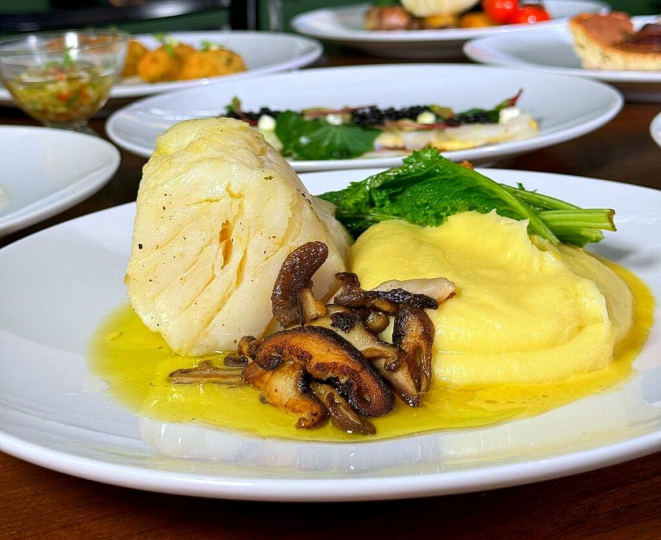 Bacalhau confitado, purê de batata, folhas de mostarda umami e cogumelos salteados, prato que vem aí no Festival de Bacalhau do Mercearia Avenida. | Foto: Divulgação