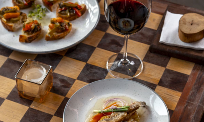 Diferentes preparos de tapas com escabeches de legumes e pescados, como anchovas e Clariana, e um dos vinhos servidos.