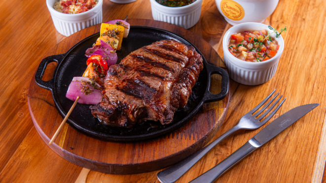 Bife chorizo assado na parrilla argentina, com arroz branco, batatas, vinagrete e chimichurri, do Churrasco ao Vivo.