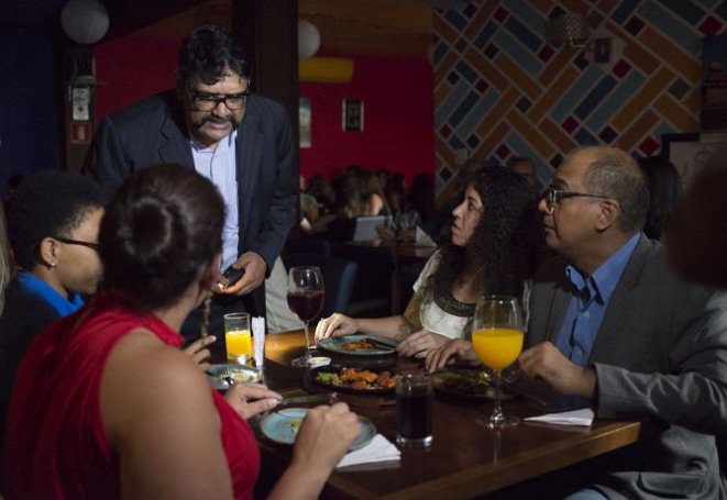 O proprietário Vijay Baraska atende uma mesa com o restaurante às escuras. Foto: Carlos Reinis/Divulgação