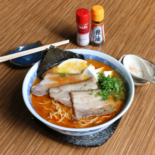 Caldo apimentado à base de frango temperado com missô, barriga de porco, ovo, cebolinha, nori e acelga.