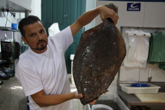 Manuel Guimarães, conhecido como Fofinho, vende ostras frescas, camarões e pescados. Na foto, exibe um filé de linguado. Foto: Juliana Gomes.