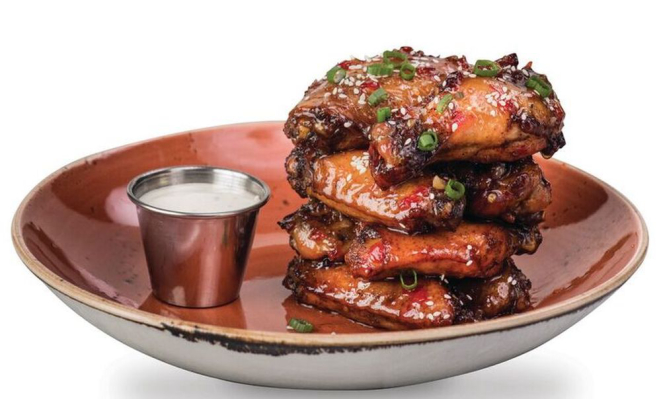 A porção de asinhas de frango com molho sriracha é um pouco mais apimentada que os outros pratos, e pode ser pedida como uma entrada para compartilhar. Foto: divulgação.