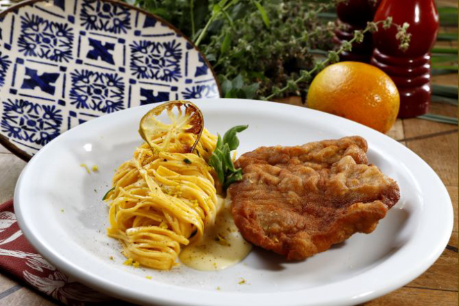 É preciso respeitar alguns passos para não errar no empanamento à milanesa. Na foto, prato que a chef Vânia Krekniski, do restaurante Limoeiro, serviu durante o Festival Bom Gourmet 2019:: cotoletta alla milanese (copa lombo suíno temperado e frito) com molho de queijo e linguini na manteiga finalizado com raspas de laranja. Foto: Antônio More / Gazeta do Povo