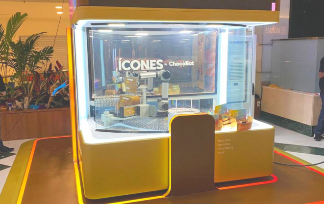 Todo o atendimento é eletrônico, com o pedido feito em um totem ao lado e a montagem da caixa por um robô. Foto: divulgação.