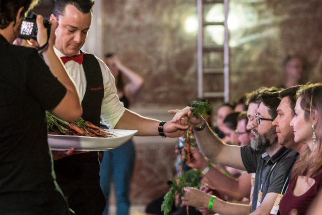 Garçom distribui à plateia cenouras 'fora do padrão' para ilustrar argumento do chef Rodrigo Bellora. Foto: Letícia Akemi/Gazeta do Povo