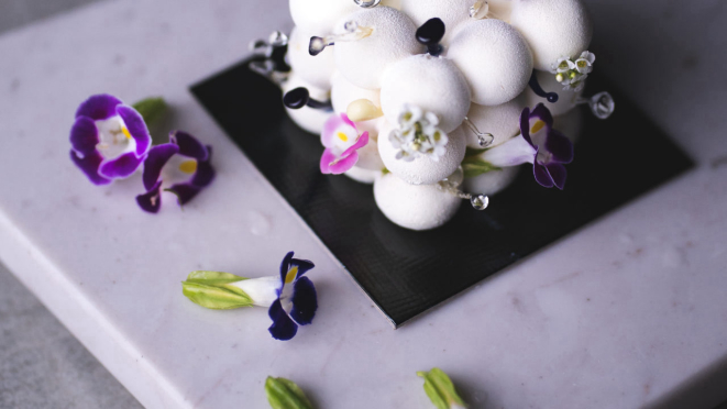 Contra-molécula, o doce feito com uma base de chocolate branco, vinho frutado, jabuticaba, romã, limão yuzu), pêssego, menta, aceto balsâmico, mostarda Dijon e shoyu. E com flores comestíveis.