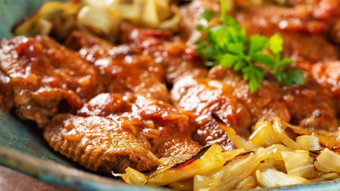 As asas de frango são finalizadas no forno e servidas sobre came de cebolas agridoces assadas.