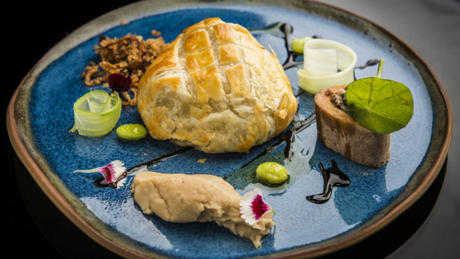 Bife Wellington, purê de feijão branco, cogumelos, sementes de edamame, tutano, tiras de salsão, folha de capuchinha e redução de framboesa.