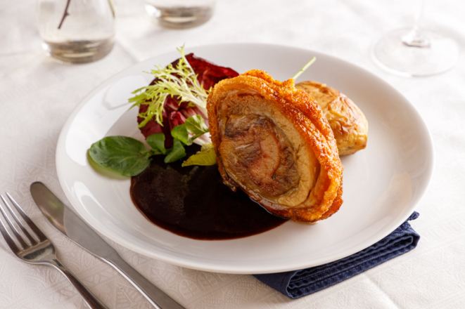 Porchetta marinada e assada lentamente com batata assada, molho de ameixa preta e salada, um dos pratos principais do Pescara Cucina Italiana.