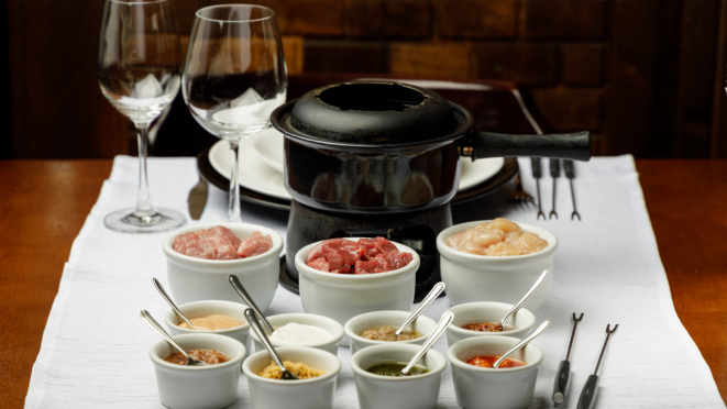 Fondue Bourguignonne, o clássico com cubos de filé mignon, peito de frango e lombinho suíno acompanhados de oito tipos de molhos, do Petit Chatêau.