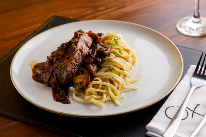 Top sirloin com molho de cogumelos e bacon servido com fettuccine ao molho à l’ancienne, uma das atrações do Ox Room Steakhouse.