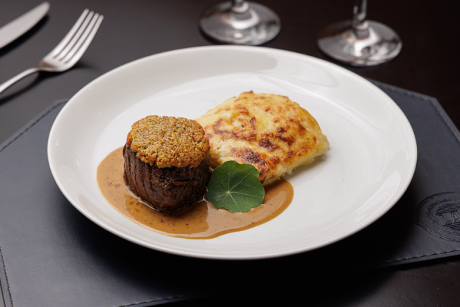 Mignon com crosta de ervas, servido com molho mostarda e batata gratinada.