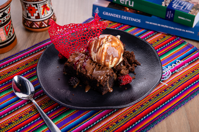 Brownie de chocolate meio amargo, servido com sorvete de creme e calda cremosa de chocolate, do QCeviche!