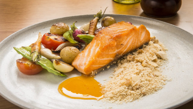 Filé de salmão assado com minilegumes caramelizados, farofa de castanhas e redução cítrica de laranja, opção de prato principal do almoço e jantar do Malauí.