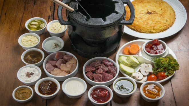 Fondue de carnes, 150 g de mignon bovino, 100 g de peito de frango e 100g de mignon suíno na pedra ou óleo, acompanha 12 molhos e batata suíça. Opção do jantar do Le Réchaud.