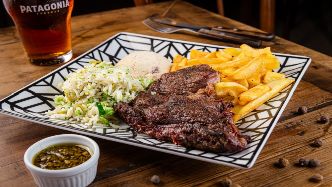 Entrecôte grelhado, acompanhado de batata frita, farofa, arroz e molho chimichurri. Prato principal do almoço e jantar do St 444 - Patagônia.